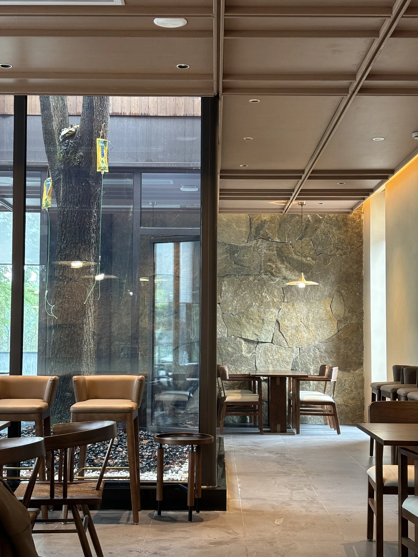 Built restaurant with courtyard planting, stone walls, timber chairs and pendant lighting