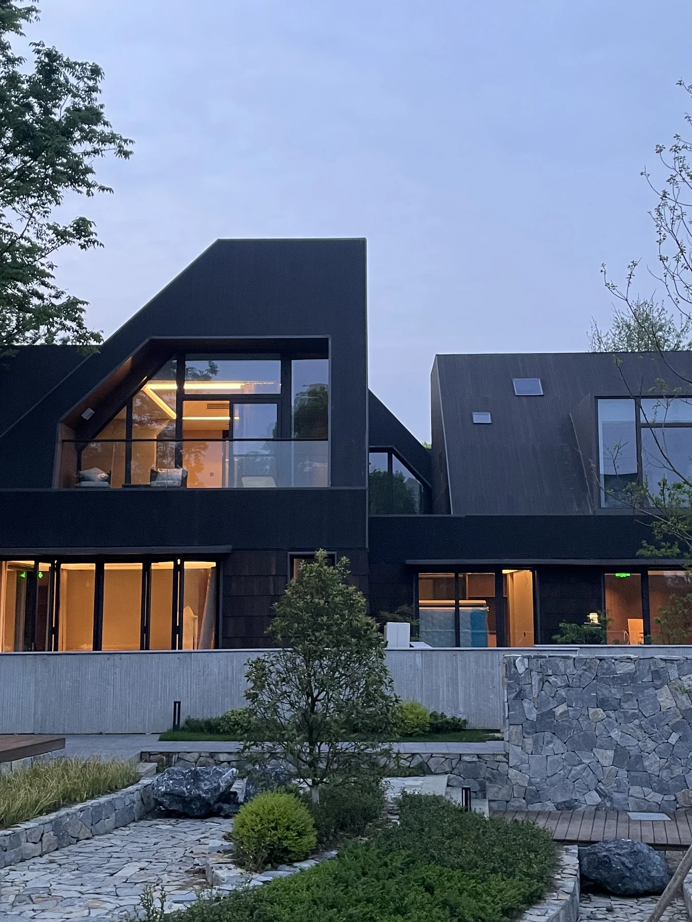 Built dark-roofed facade beside courtyard water and landscaped planting
