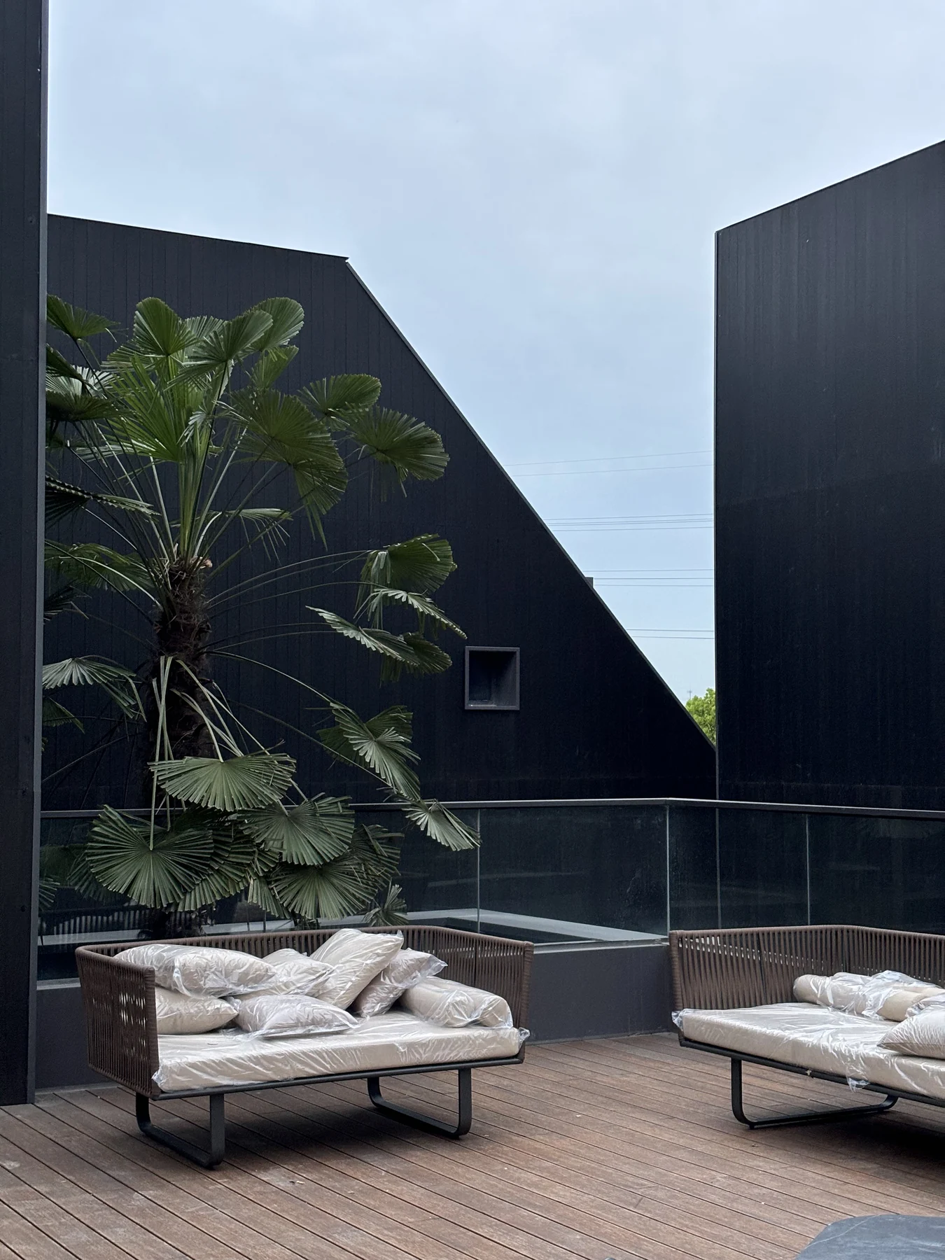 Built terrace furnished with outdoor sofas beside planting and dark facades