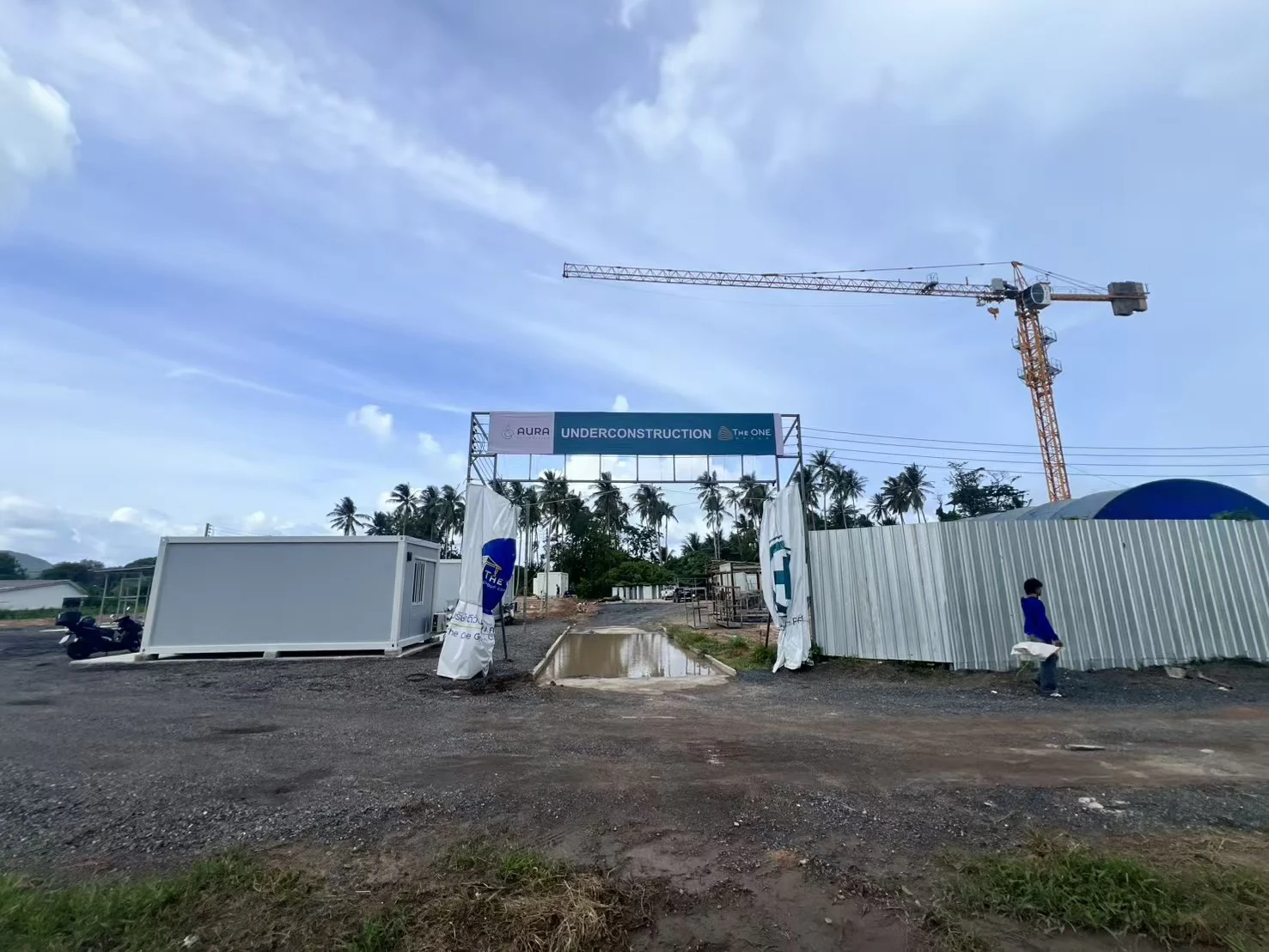 Construction-progress photograph of the site entrance and hoarding at The One AURA Hotel in 2026